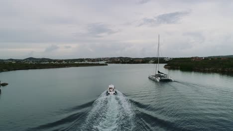 Toma-Aérea-De-Un-Barco-En-La-Playa-De-Santa-Bárbara-Toma-Aérea-De-Gran-Altitud-De-Una-Playa-Privada-En-La-Isla-Caribeña-Holandesa-De-Curaçao,-Ubicada-En-El-Sureste-De-La-Isla