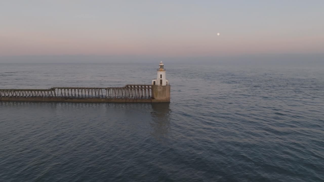 Aerial views of Blyth Harbour’s lighthouse as the evening moon lights up the twilight horizon.
