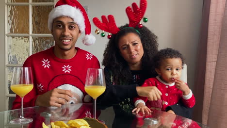 Young-Parents-with-Small-Child-On-Christmas-Video-Call-Trying-to-Guess-Acted-Word-During-Charades