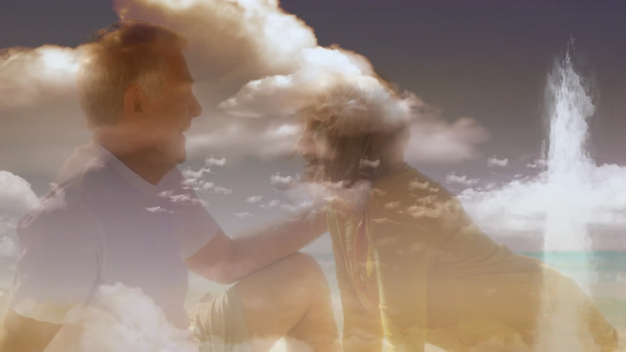 On beach, elderly couple watching animation of fluffy clouds in sky