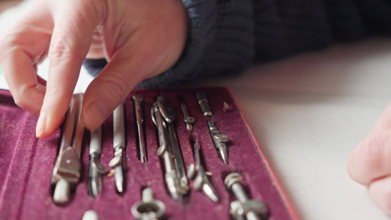 Hands reveal a refined set of drafting tools in a velvet box, conveying precision, craftsmanship, and focused design work. Ideal for architecture, engineering, and creative process storytelling
