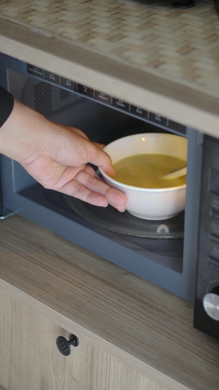 Mano che prende una ciotola di zuppa dal microonde