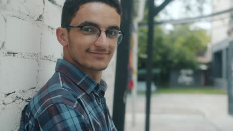 young man smiling by a brick wall