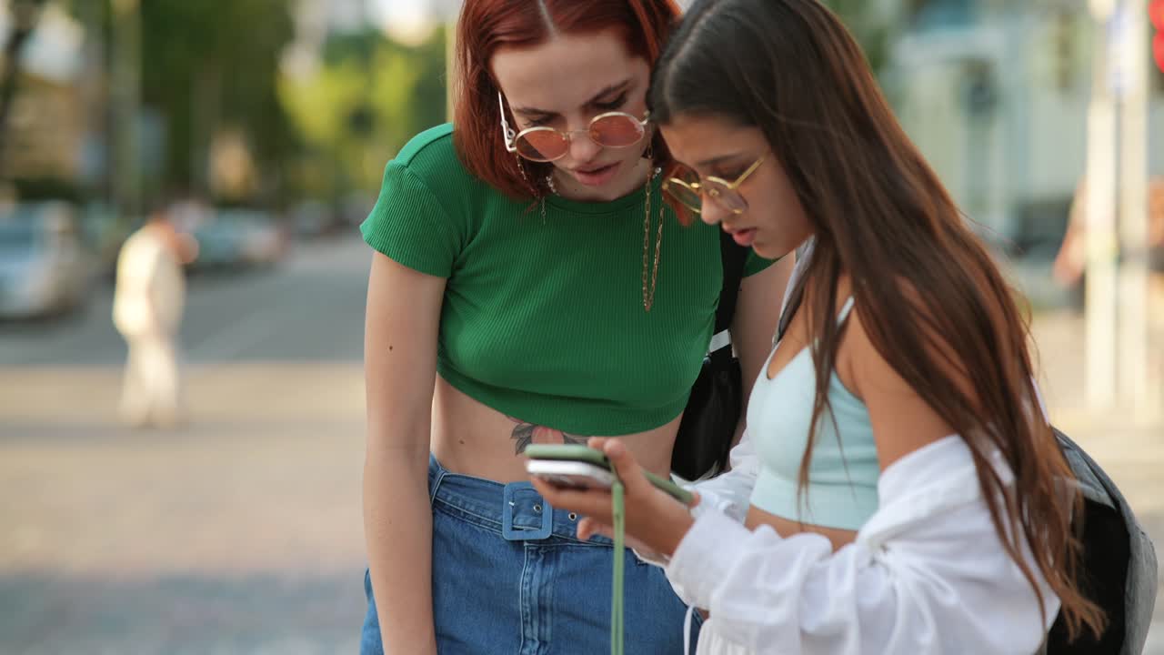 dos mujeres jóvenes mirando un teléfono inteligente