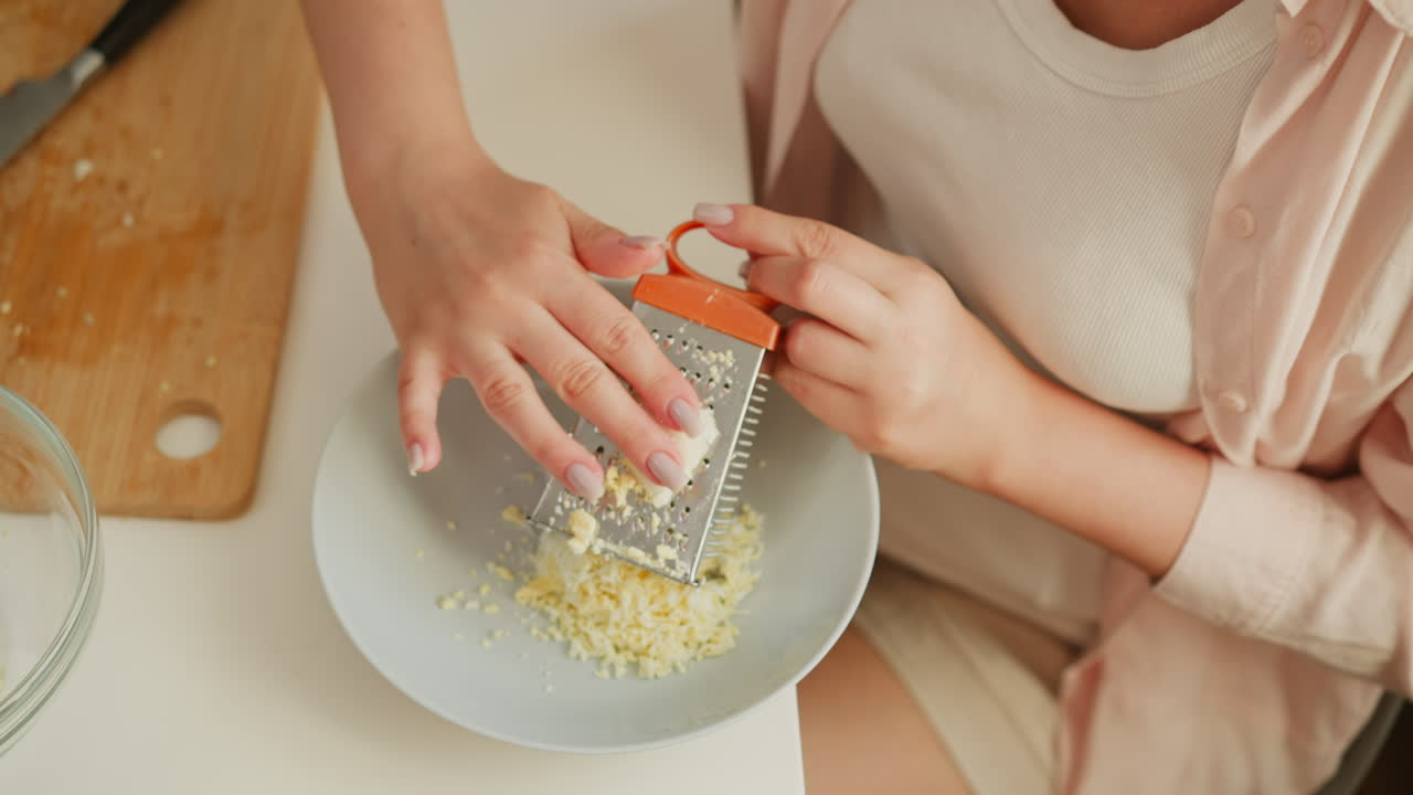 Donna che grattugia le uova in cucina.