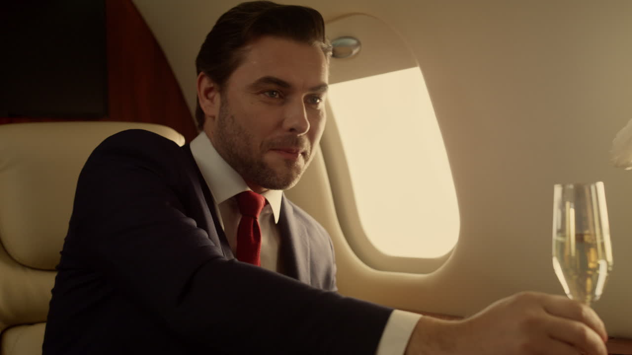 Imprenditore sorridente che si rilassa in jet, primo piano. Donna attraente che beve champagne sotto la luce del sole.