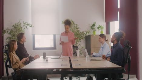 pregnant woman explaining a project in front of her coworkers in a meeting room