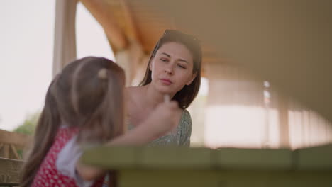 Careful-mother-wipes-girl-face-at-lunch-in-hotel-restaurant