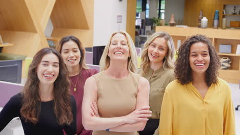 portrait of smiling multi-cultural female business team standing in modern open plan office