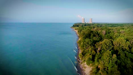 Aerial-view-of-a-coastline-with-a-power-plant-off-in-the-distance