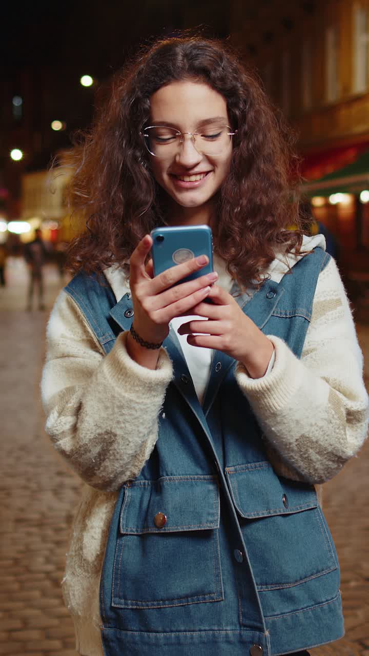 chica feliz usando teléfono inteligente escribiendo mensajes de texto navegando por internet terminando el trabajo mirando a la cámara