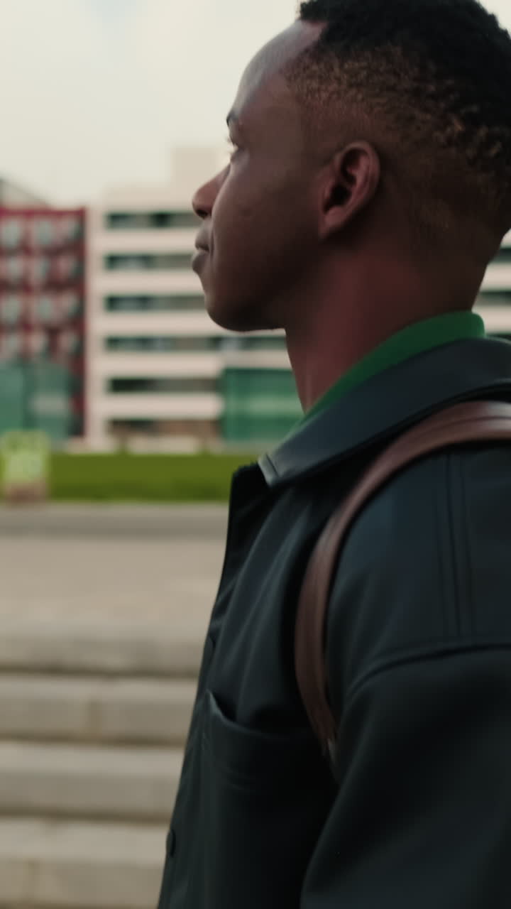 Side Profile of Young Black Man Walking Outdoors with Backpack
