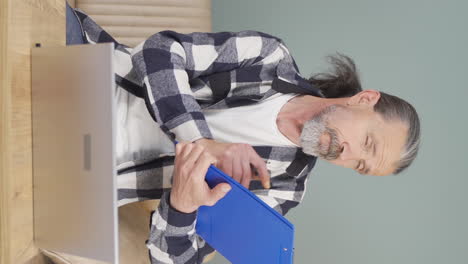 Vertical-video-of-Old-man-with-notebook-thinks-and-takes-notes.