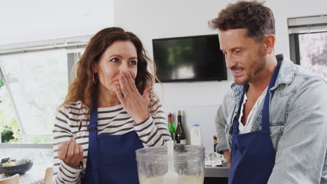 hombre y mujer participando en una clase de cocina degustando comida