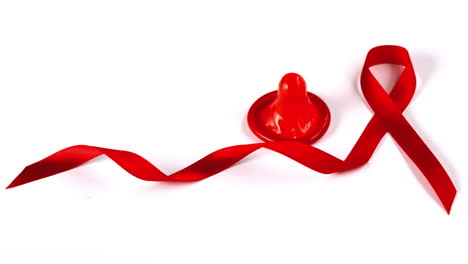 condom dropping down beside aids red ribbon symbol