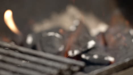 pan and rack focus to burning charcoal briquettes in bbq pit