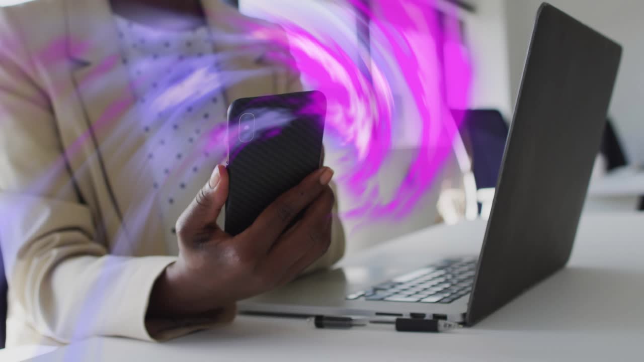 Woman holding phone near laptop, purple swirl sweeping across hands, causing tapping for app test