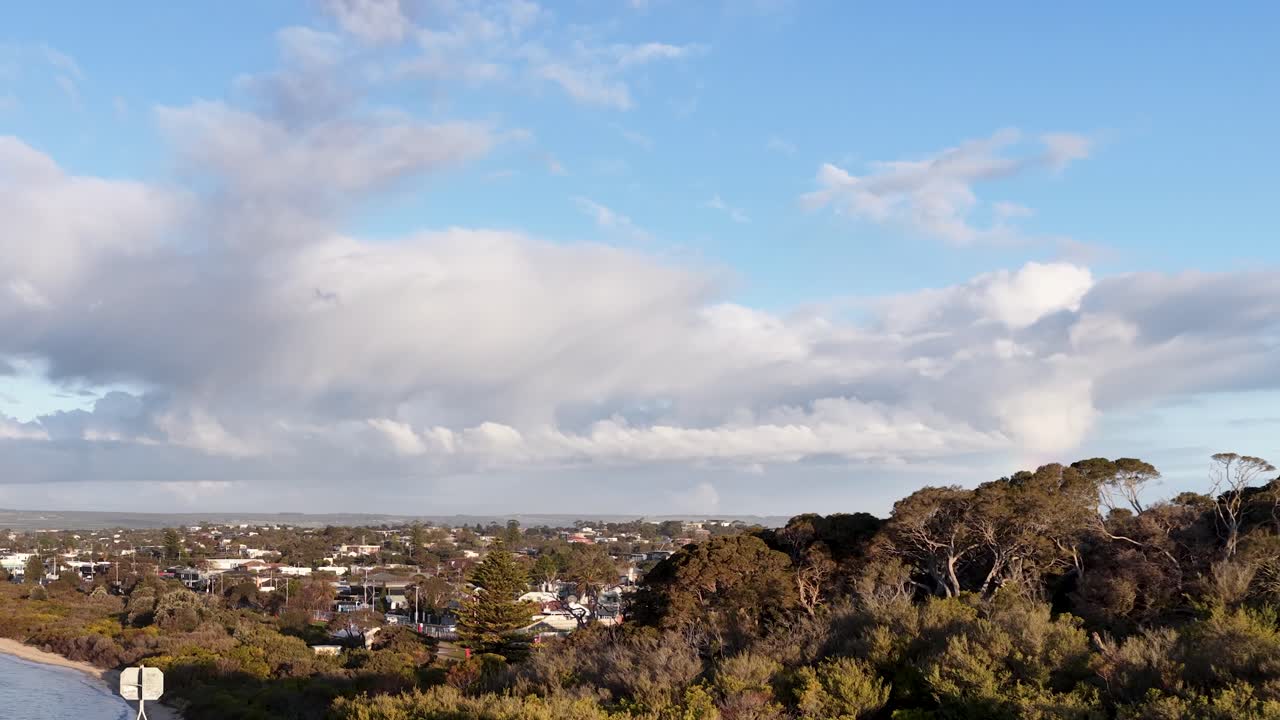 Aerial camera pans over Rye suburb, revealing houses, trees, and dramatic evening sky with clouds