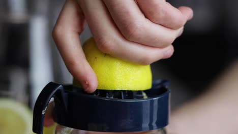 half of a lemon being squeezed on a juicer by hand