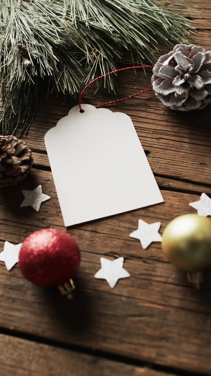 Vertical video of christmas decorations and gift tag with copy space on wooden background