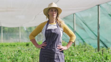 Video-of-happy-caucasian-woman-wearing-apron-and-standing-in-greenhouse