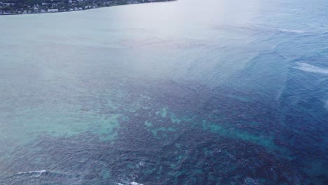 imágenes de drones mirando hacia el agua clara del océano con arrecifes de coral alineando el fondo del océano inclinándose hacia arriba para recibir la costa de la isla de oahu cerca de la playa de lanikai hawai