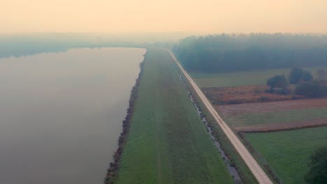 landscape with a simple road bordering a lake at foggy autumn morning in central europe