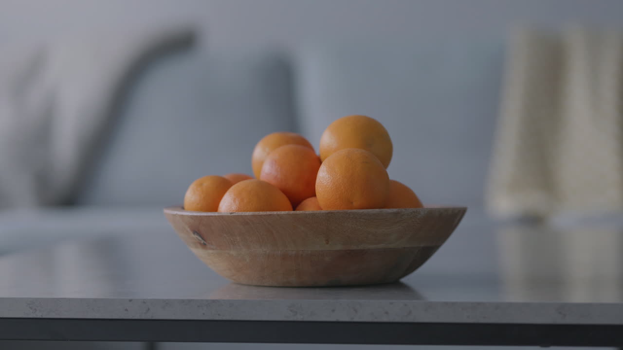 Wooden bowl filled with fresh organic Italian blood oranges on a modern table