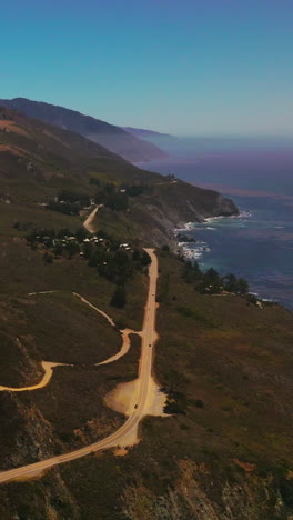 roads passing through uneven mountainous landscape of california coastline. pine tree forest overgrowing the mountain tops. aerial perspective. vertical video