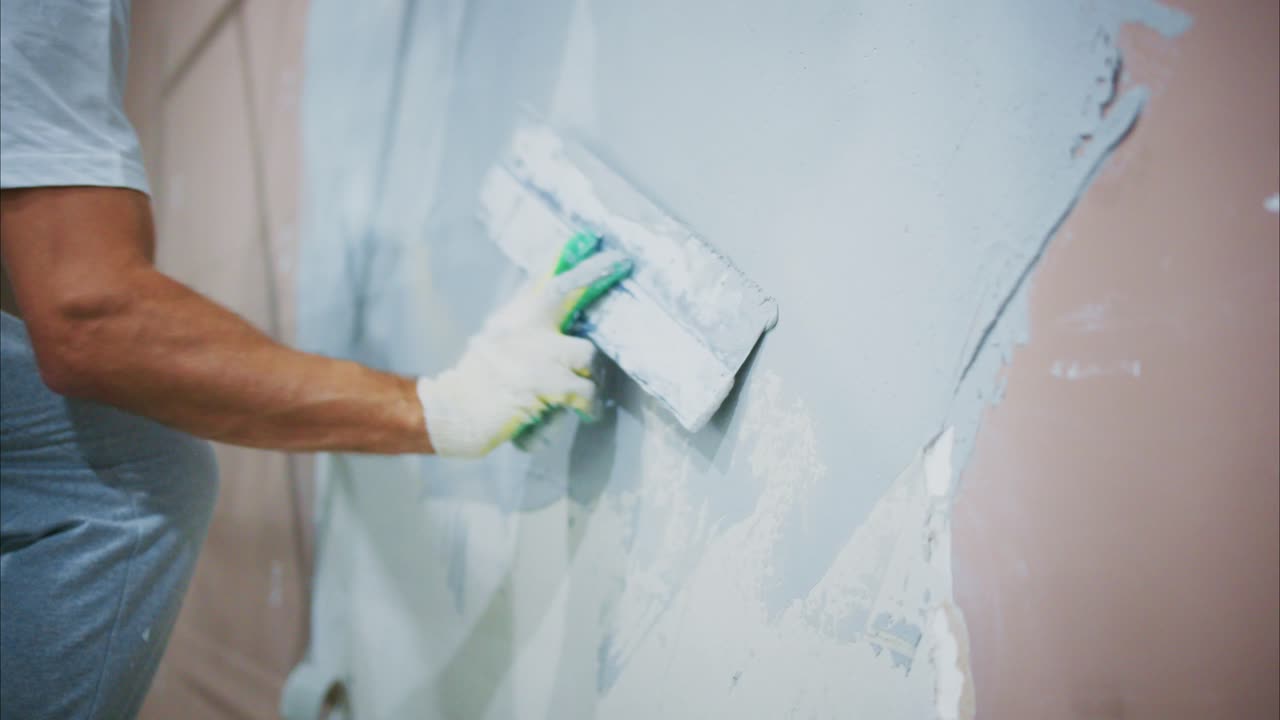 A Skilled Craftsman Applying Smooth Gray Paint to a Wall, Showcasing the Art of Interior Finishing with Precision and Care in Home Renovation