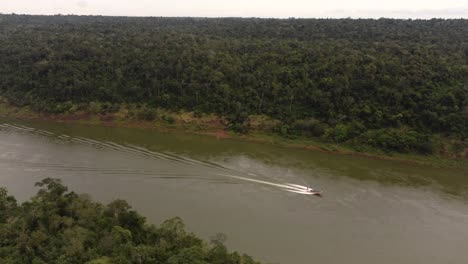 Aerial-birds-eye-shot-of-motorboat-cruising-over-Amazon-River-in-Amazon-Rainforest