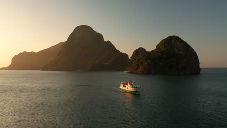 Antena-Que-Muestra-Un-Gran-Ferry-Que-Va-Al-Puerto-De-El-Nido-Con-Puesta-De-Sol,-Palawan,-Filipinas