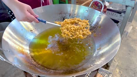 frying food in a large pan in bangkok