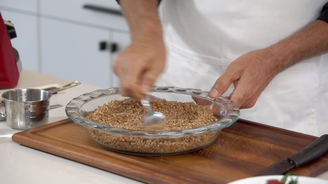 Spargere granella di mandorle e noci tritate per la base di una cheesecake vegana fatta in casa, senza latticini e a base vegetale, per un'alimentazione sana.