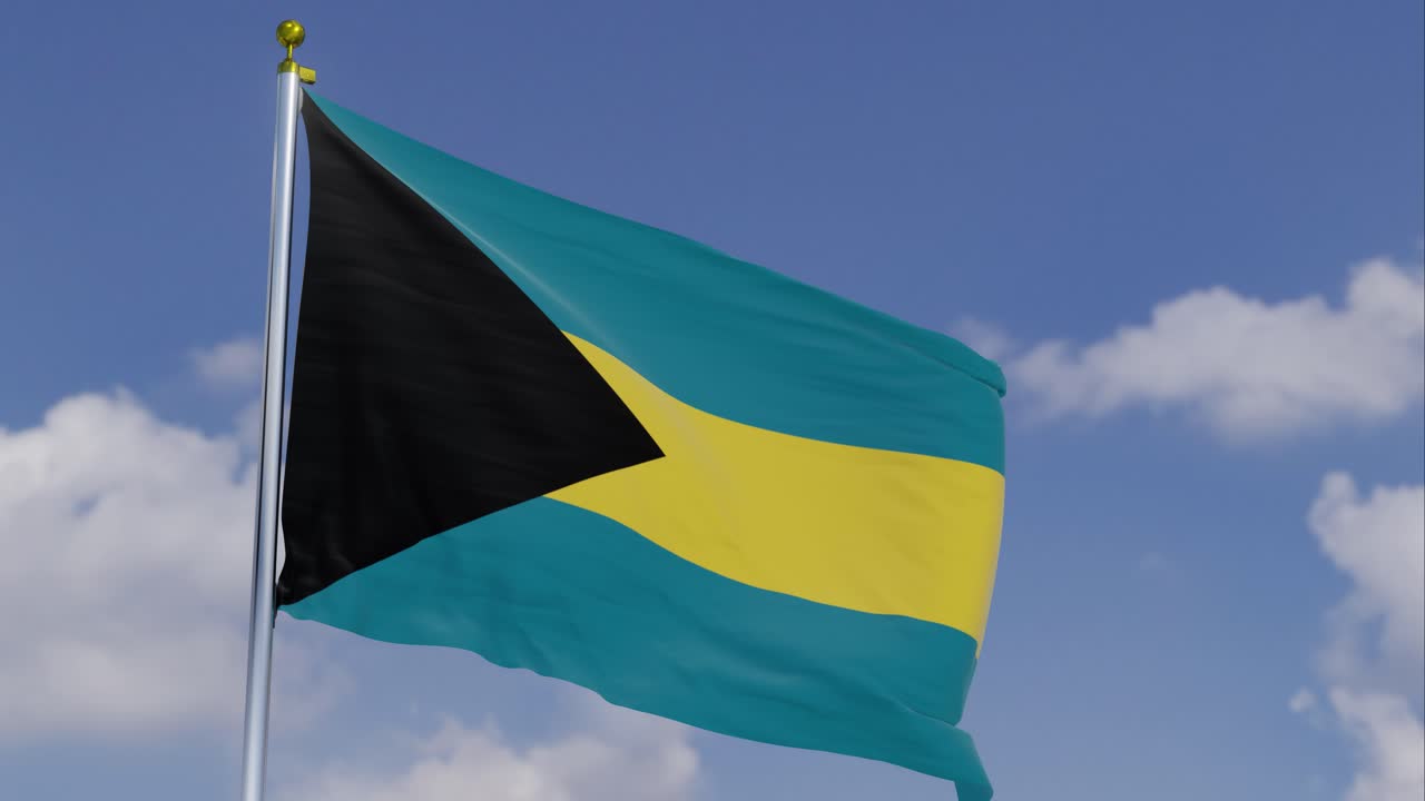 Flagge der Bahamas flattert im Wind vor klarem blauem Himmel im Hintergrund, langsam ziehende Wolken, Fahnenmast, Zeitlupe