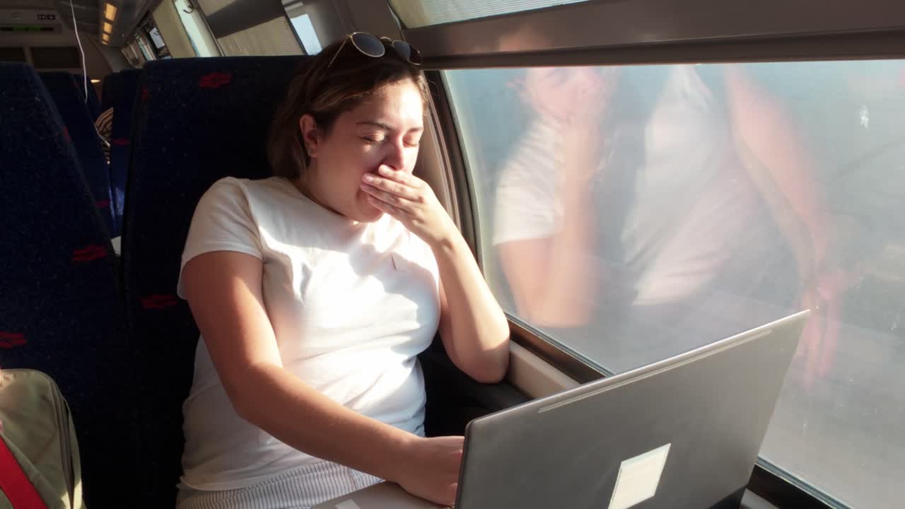 Exhausted Young Woman Yawning While on a Train Commute