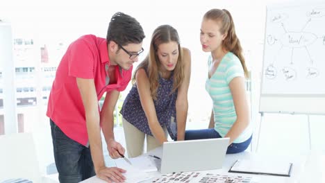 Creative-team-having-a-meeting-looking-at-contact-sheets-and-laptop