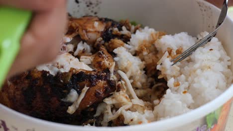 close-up of a person eating delicious grilled chicken and rice with coleslaw