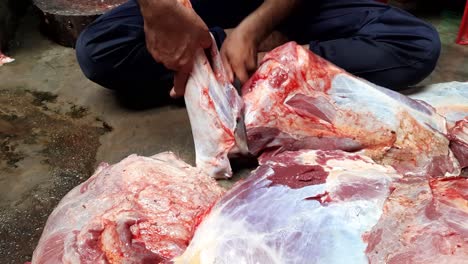 a group of workers in a meat factory chopped fresh beef meat in pieces on a work table using knives of industry food