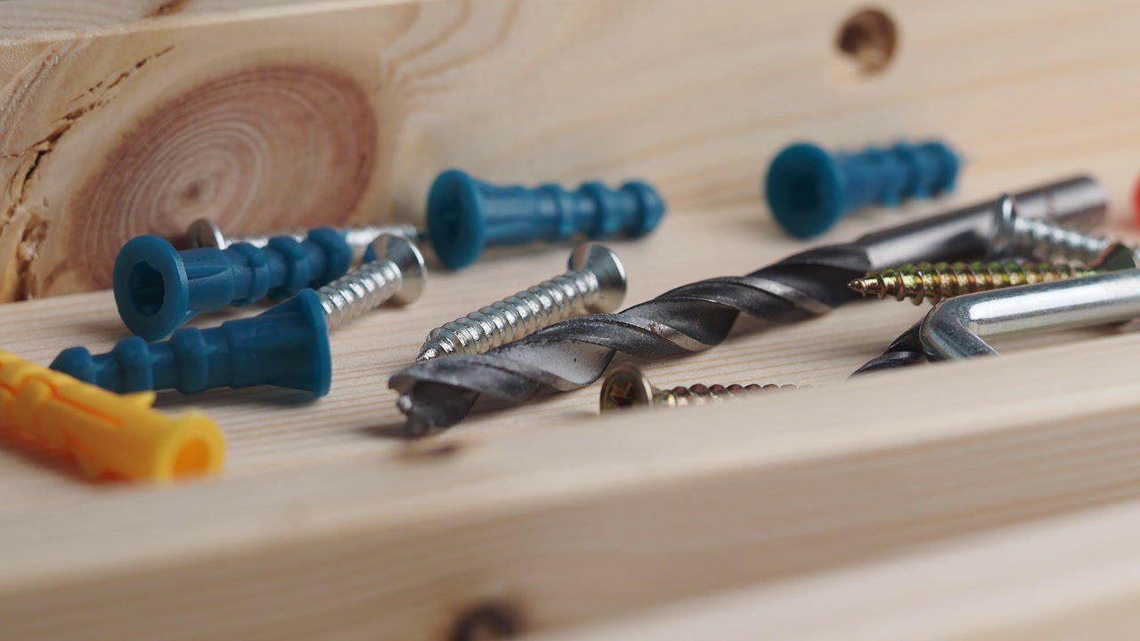 Assortment of Screws, Drill Bit, and Wall Plugs on Wood