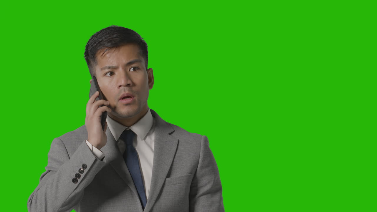 Studio Shot Of Angry Businessman In Suit Talking On Mobile Phone Against Green Screen 1