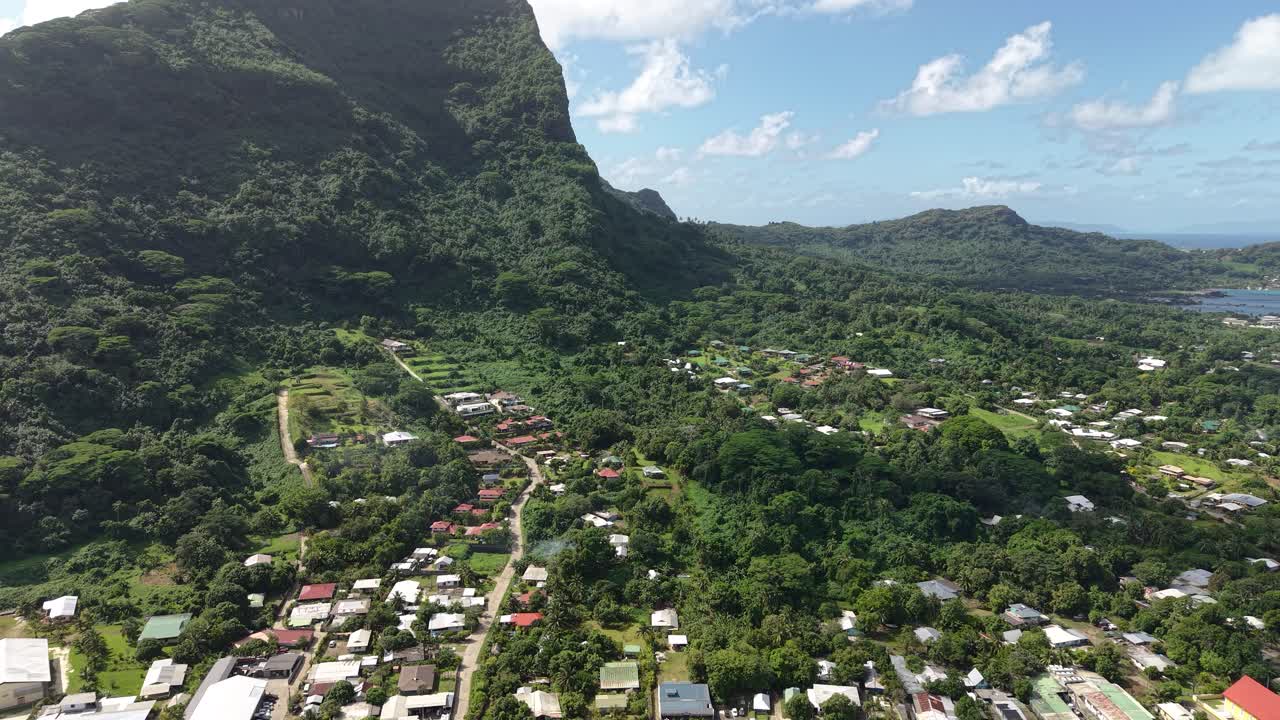 Aerial View of a Village Surrounded by Mountains and Lush Vegetation