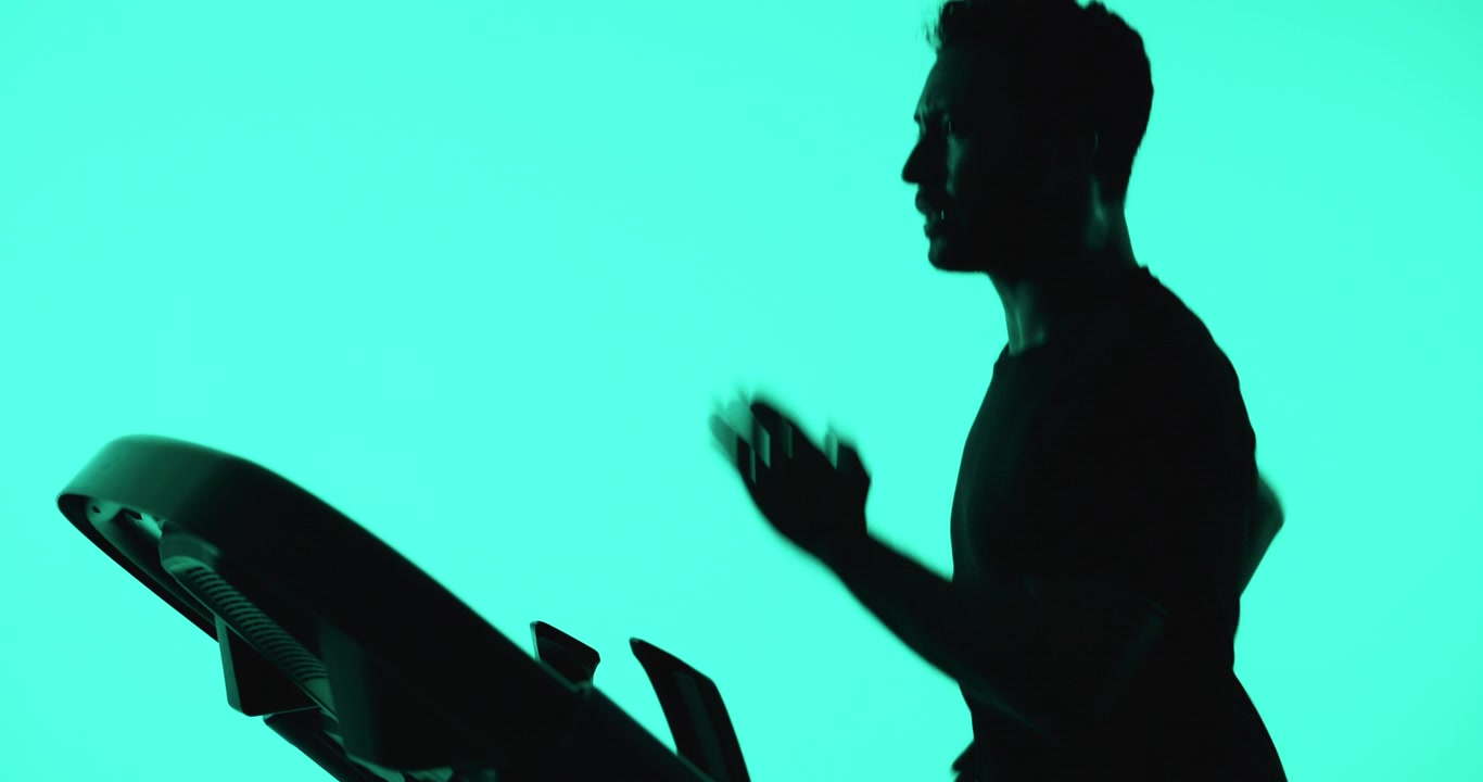 Silhouette di un uomo che corre sul tapis roulant su sfondo verde