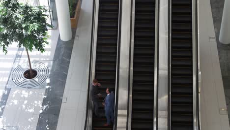 hombres de negocios en una escalera mecánica en un edificio moderno