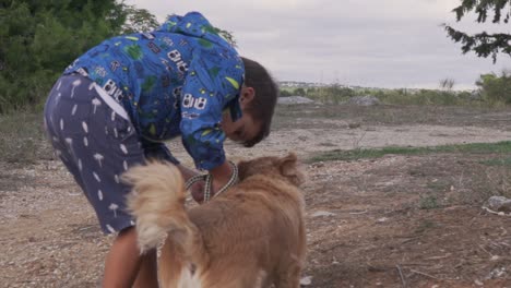 Caucasian-boy-toddler-unleash-a-medium-sized-Kokoni-breed-dog,-out-in-the-fields-,-slow-motion-120fps