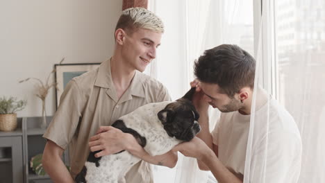 two gay men petting cute dog at home