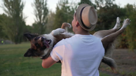 young man with his dog in his arms, on his back, dog looking at camera
