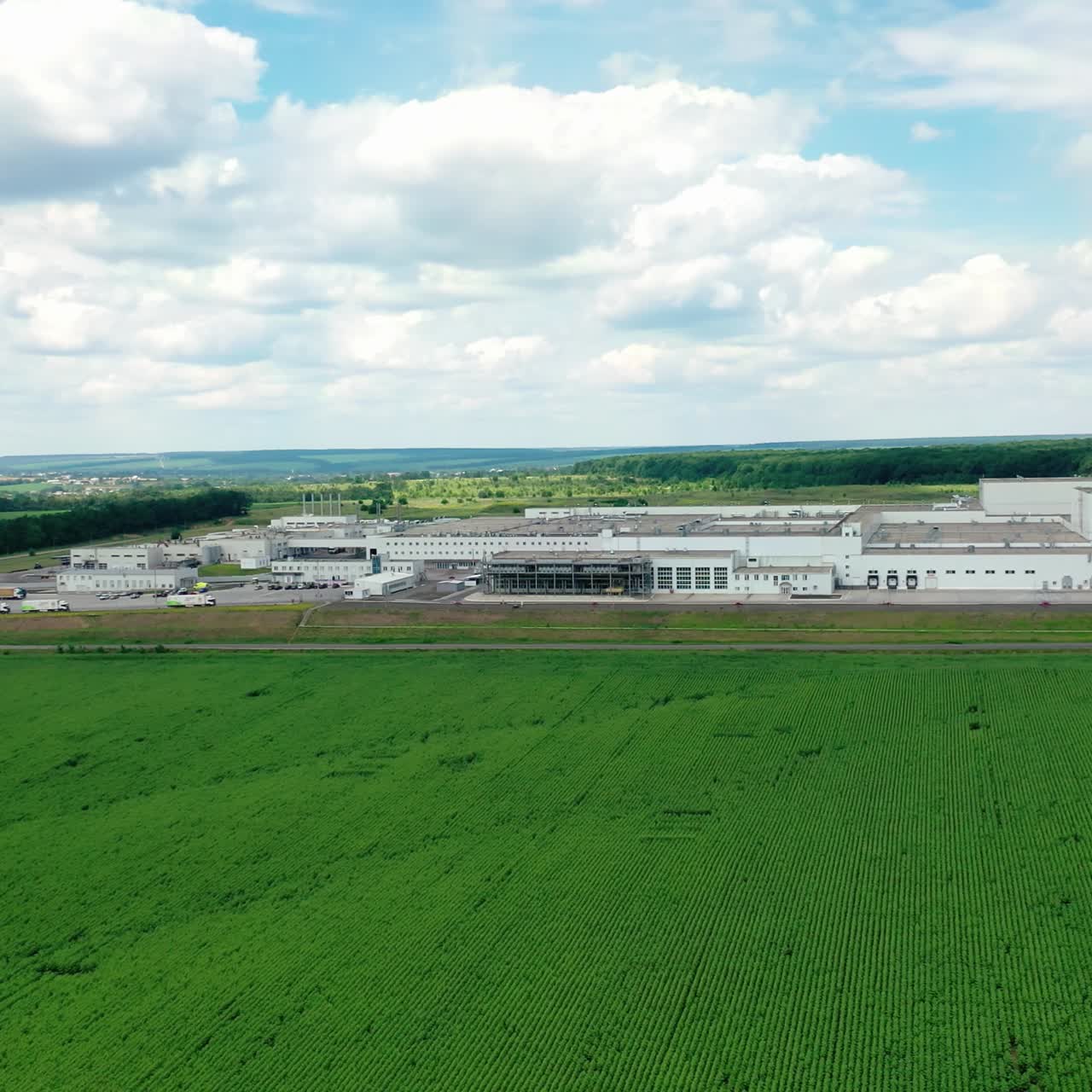 Modern industry among amazing green scenery. Large industrial complex on field in summer. Harmful manufacturing in nature. Aerial view