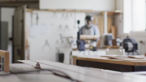 african american male carpenter wearing protective helmet turning wood on a lathe at carpentry shop