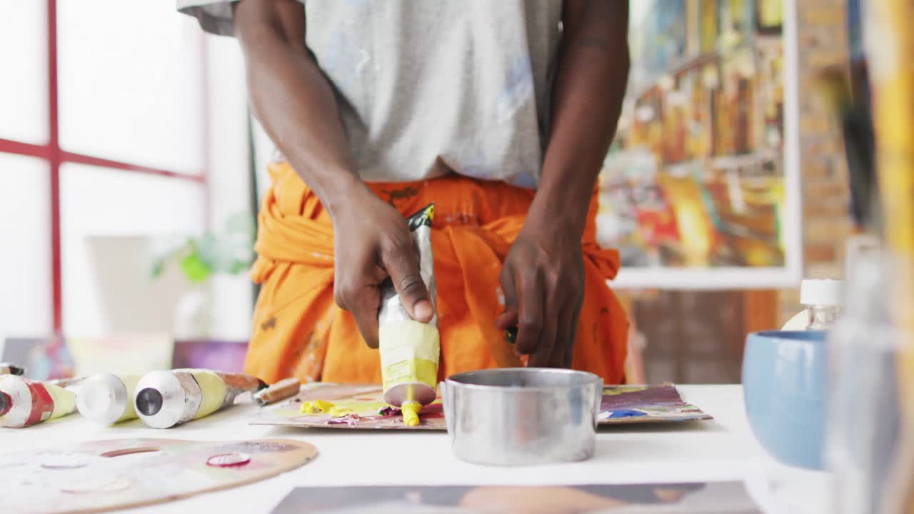 Midsection of african american male painter mixing paint in artist studio